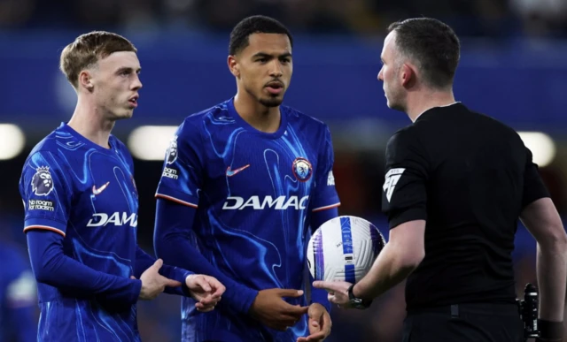 Referee Chris Kavanagh speak to Chelsea's Levi Colwill and Cole Palmer