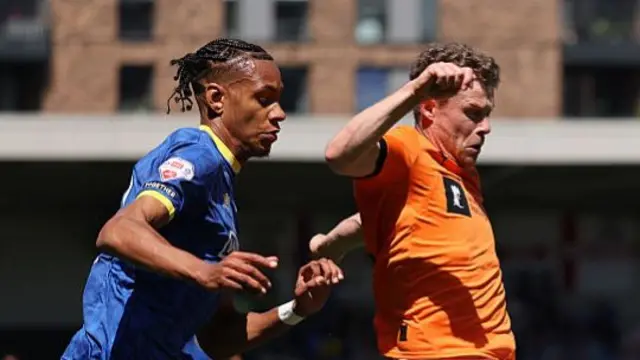 Matt Palmer shields the ball in an orange vest for Notts County