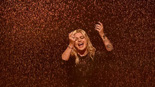 Louane surrounded by a wall of sand