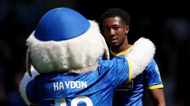 Josh Neufville is congratulated by AFC Wimbledon's mascot