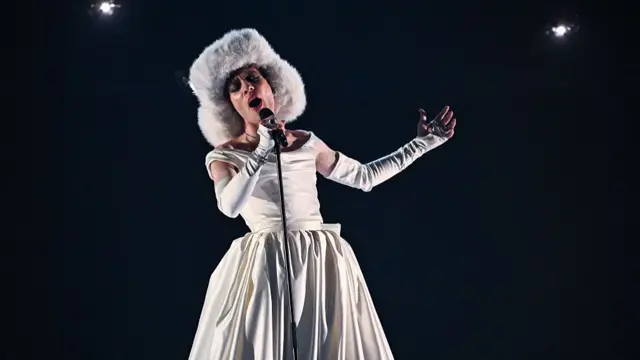 Nemo performs in a fluffy hat and white wedding gown