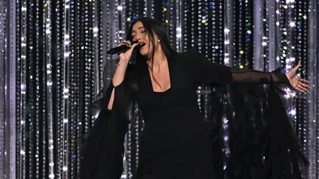 Israel singer in black dress in front of sequined curtain