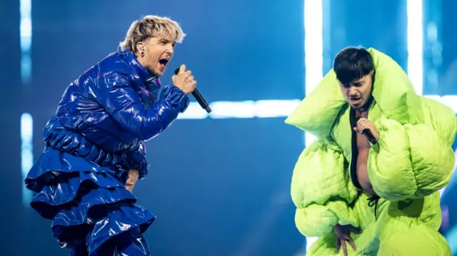 Baby Lasagna in blue suit and Kaarija in Green suit perform on stage