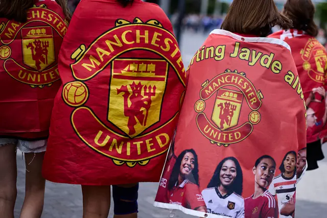 Two Manchester United fans with Manchester United flags wrapped around them