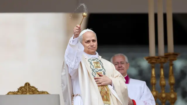 Pope Leo stands and sprinkles holy water