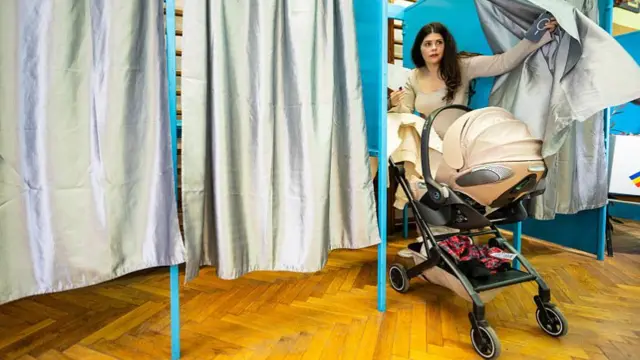 A woman exits a voting booth at a polling station in Bucharest, Romania on May 18, 2025