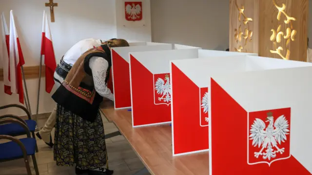 People, wearing traditional clothes, prepare to vote during the first round of Poland's presidential election at a polling station in Poronin, Poland