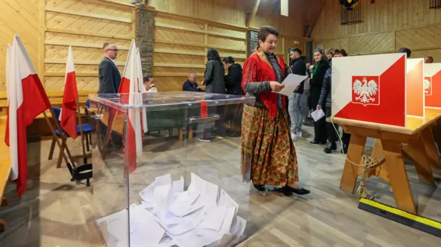 A person, wearing traditional clothes, prepares to vote during the first round of Poland's presidential election at a polling station in Poronin, Poland, May 18, 2025