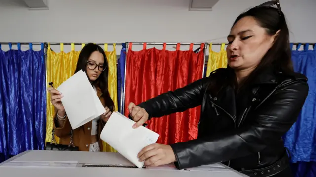 Two Romanian women cast their ballots in the second round of presidential elections at a polling station in Bucharest, Romania, 18 May 2025