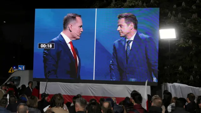 Karol Nawrocki, a candidate for Polish presidential election supported by Poland's main opposition party Law and Justice (PiS), and Civic Coalition presidential candidate, Warsaw mayor Rafal Trzaskowski, are seen on a screen during the presidential candidates' election debate, in front of the Polish Television headquarters in Warsaw, Poland