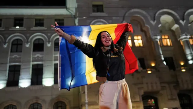 A Nicusor Dan supporter holds up a Romanian flag in Bucharest, as she reacts to exit polls. Photo: 18 May 2025