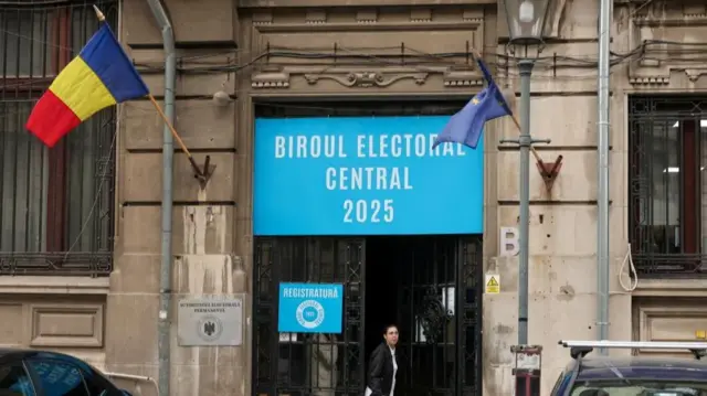 A building with a Romanian and EU flag outside with a sign reading 'Biroul Electoral Central 2025'