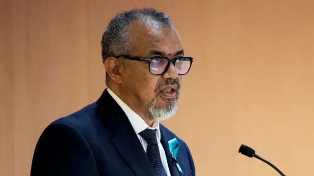 Tedros Adhanom Ghebreyesus stands in front of microphone