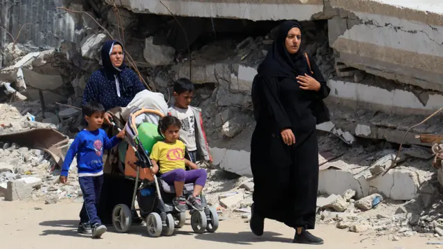 A Gazan family pushes their belongings in a buggy as they leave Khan Younis