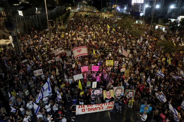Demonstrators in Tel Aviv on Saturday night hold a banner that says "the fighting kills the hostages"
