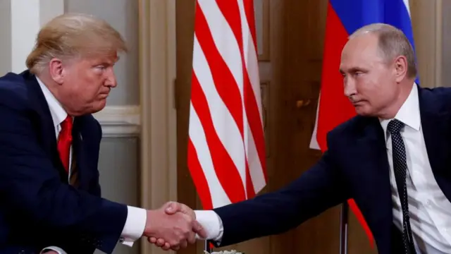 Putin shakes hands with Trump.