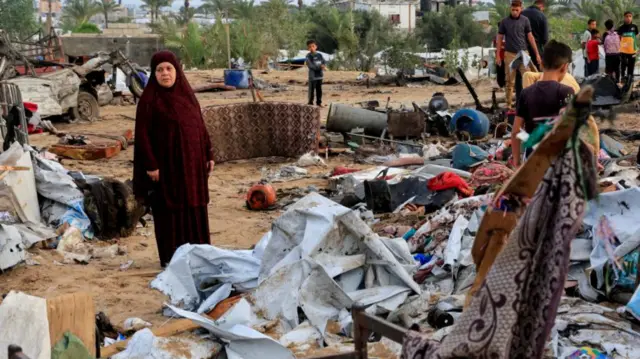 Palestinians inspect the site of an Israeli strike on a tent camp, in Khan Younis, southern Gaza, on Sunday