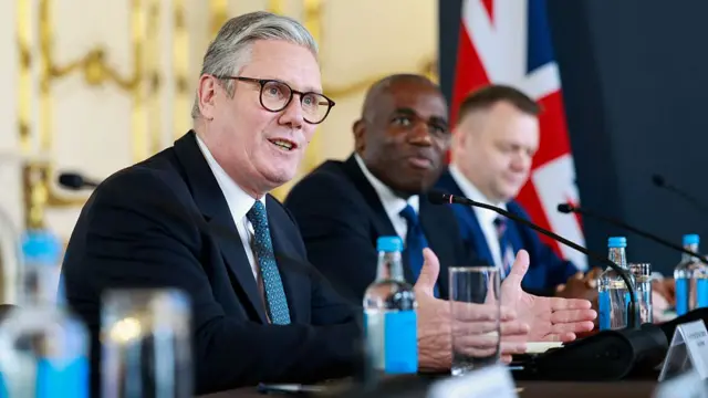Kier Starmer sitting beside David Lammy at a table, gesticulating whilst speaking.