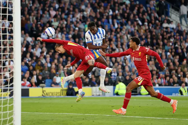 Danny Welbeck of Brighton & Hove Albion creates a headed chance under pressure from Kostas Tsimikas and Jarell Quansah of Liverpool