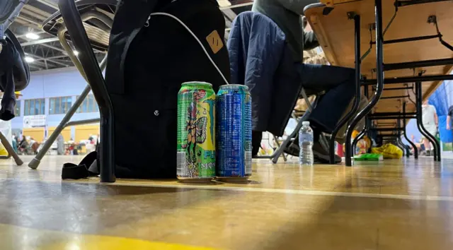 A couple of cans of energy drink under a desk