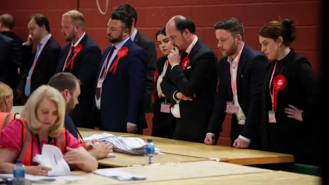 A line of Labour party officials watch the process of recounting votes