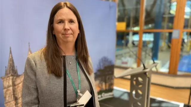Lucy Townsend, wearing a grey top, looking at the camera. She has long brown hair