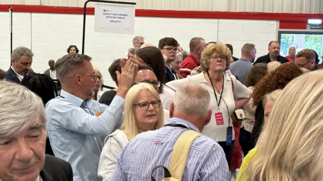 A crowd of Lib Dems clapping inside the sports hall.