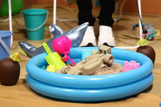 A paddling pool with a Formula 1 car made of sand in it