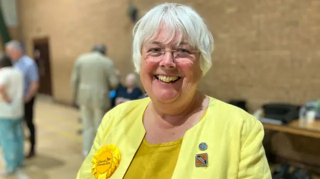 Charlotte wearing a yellow dress and a yellow jacket