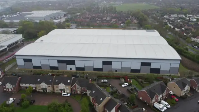 Aerial shot of a large warehouse by a housing state