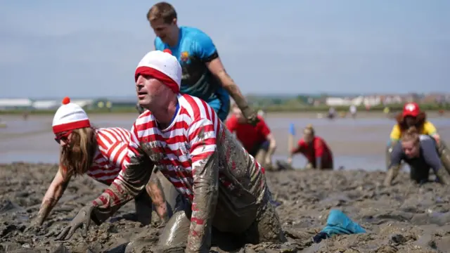 Competitors dressed as Wally take part in the mud race