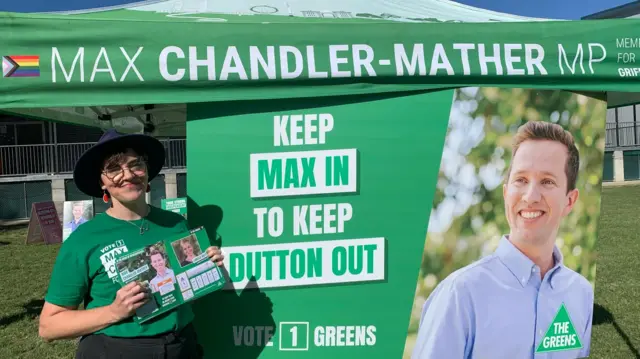 A female volunteer wearing Green promotes the Green Party on election day.