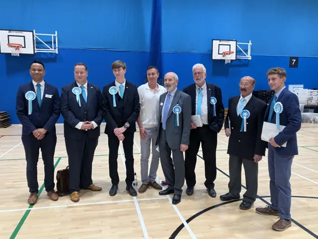A group of men in suits with blue Reform badges