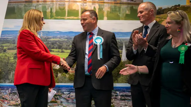 The candidates shake hands after the result has been read out