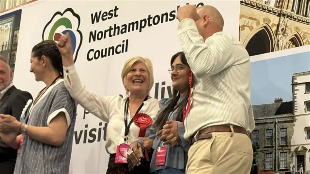 A man and a woman pump the air on stage as they win a seat.