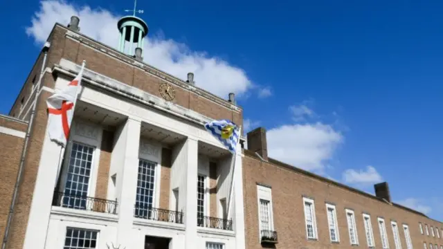 A picture of Hertfordshire County Council's offices in Hertford. It is a brown brick building, with white bits too, and there is blue sky behind it