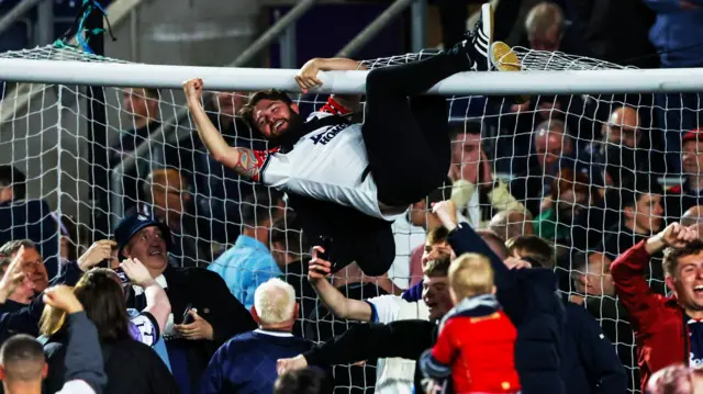 A Falkirk fan swings on the crossbar