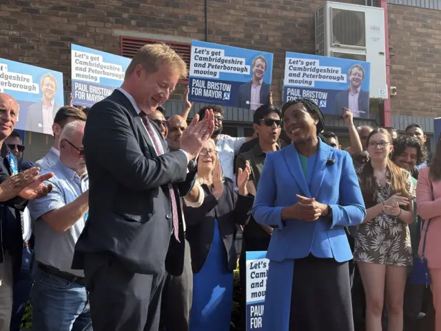 Bristow wearing a blue suit standing next to Kemi wearing a blue blazer