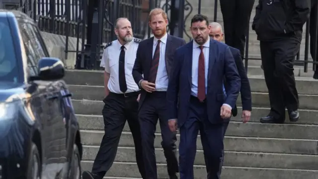 Harry walks down steps surrounded by members of his security team