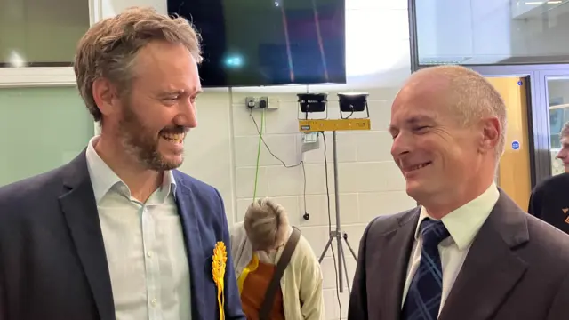 Two men are standing next to each other and laughing.