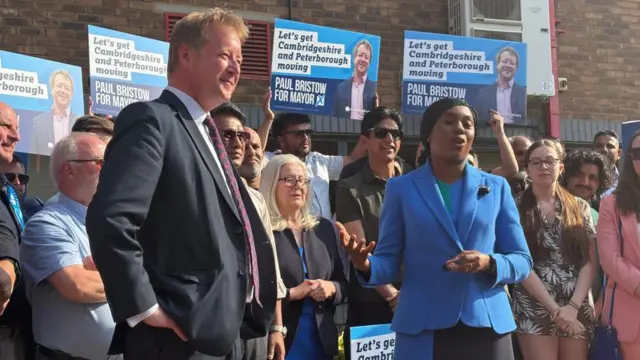 Paul Bristow and Kemi Badenoch with a group of people behind them