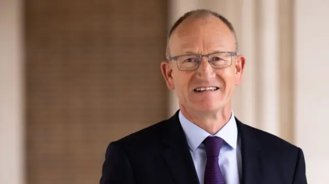 Conservative leader Richard Roberts - he has short hair and is wearing glasses, a dark blue jacket, with a light purple shirt and a purple tie