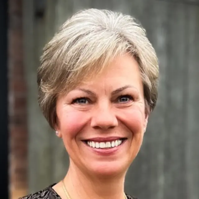 A smiling woman with short blonde hair