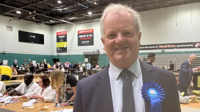 Councillor Andrew Williams standing in a room where votes are being counted