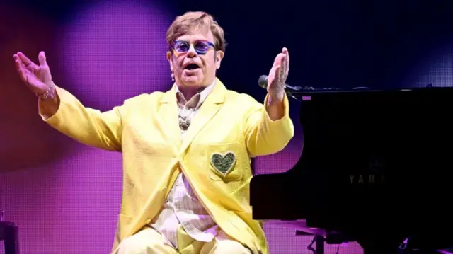 Elton John sits at a piano