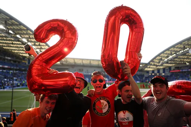 Liverpool fans pose for a photo while holding balloons