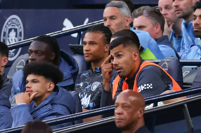 Rodri of Manchester City (R) looks on from the substitutes bench