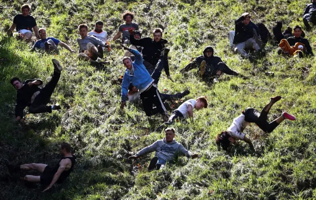 A group of people travel down Cooper's Hill at high speed as part of the Gloucestershire cheese rolling event