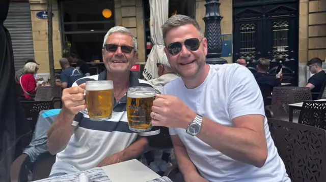 A father and son, who both support Tottenham, pose for a photo in Bilbao while each holding a beer