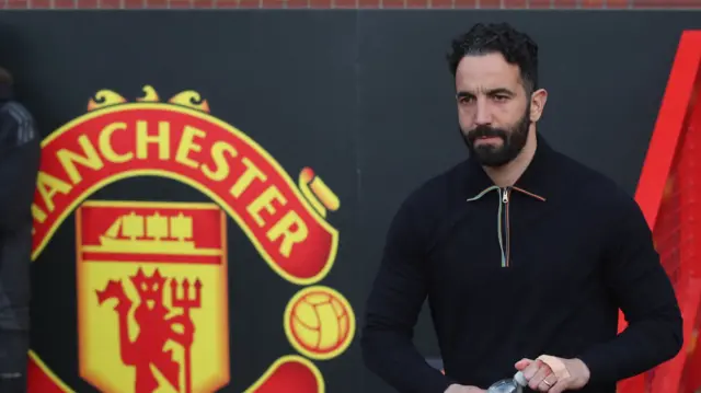 Manchester United head coach Ruben Amorim opens a bottle while stood in front of the Old Trafford dug-out